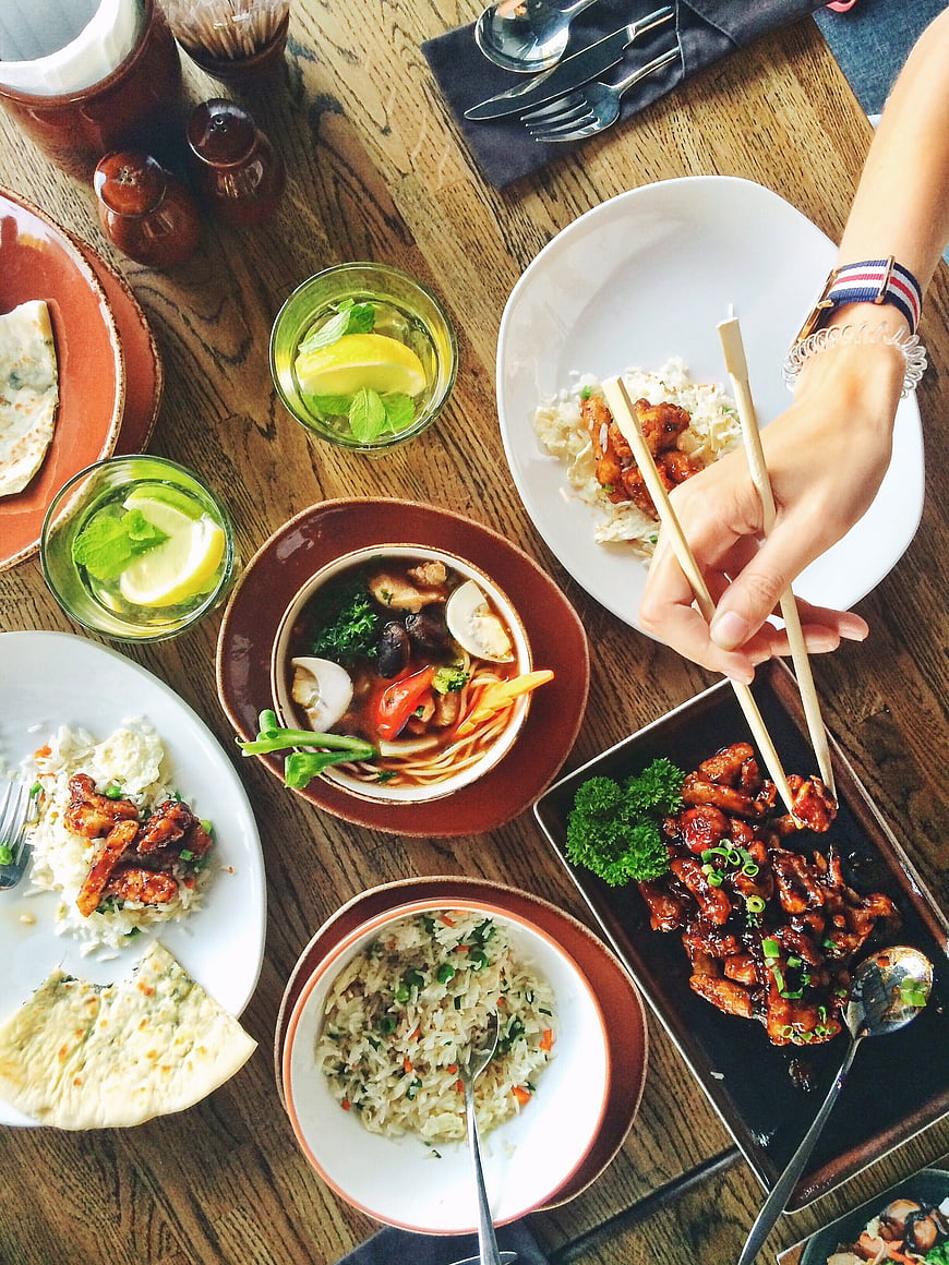 Overhead view of Asian food feast with chopsticks on wooden table