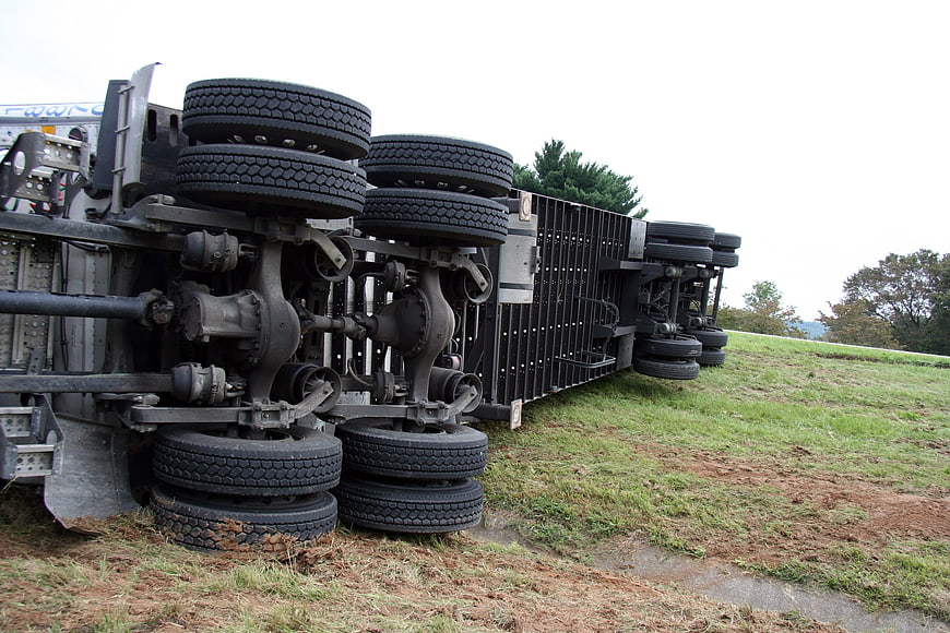 Overturned semi-truck trailer on grassy roadside