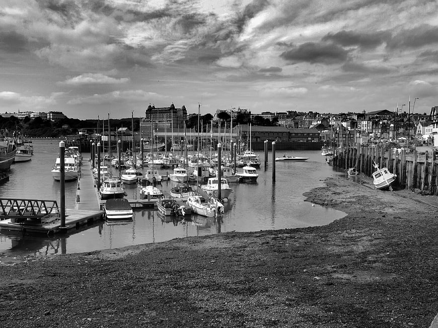 Black and white harbor scene with boats at low tide