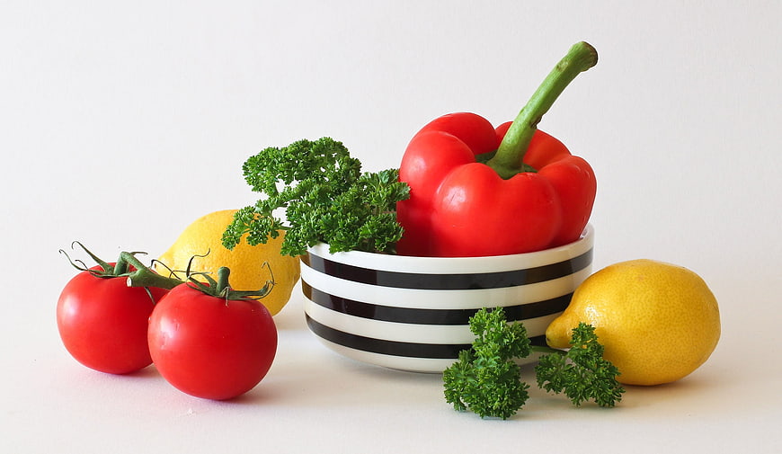 Fresh Red Bell Pepper, Tomatoes, Lemons, and Parsley in Striped Bowl