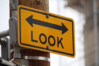 Yellow Look Traffic Sign with Arrows on Rusty Pole