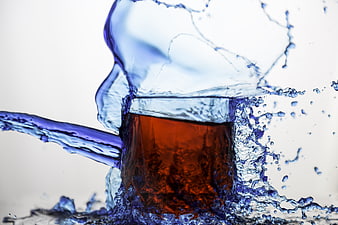 Dynamic Splash of Clear Water Surrounding Amber Liquid in Glass