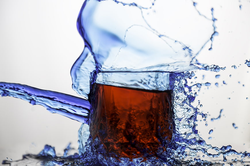 Dynamic Splash of Clear Water Surrounding Amber Liquid in Glass