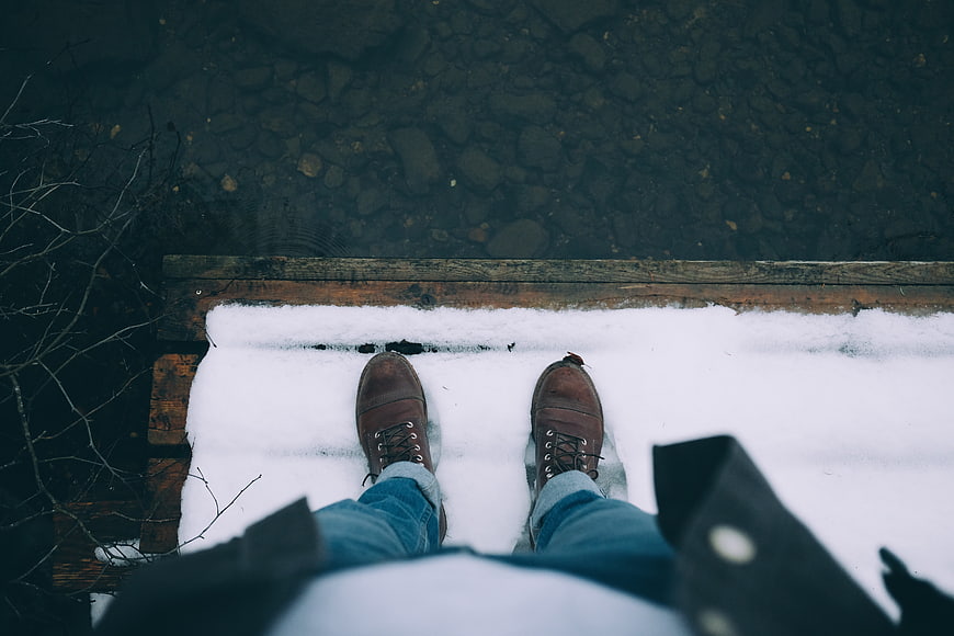 First-person view of brown boots on snowy wooden dock