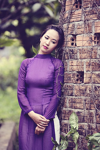 Woman in Purple Ao Dai Leaning Against Old Brick Wall