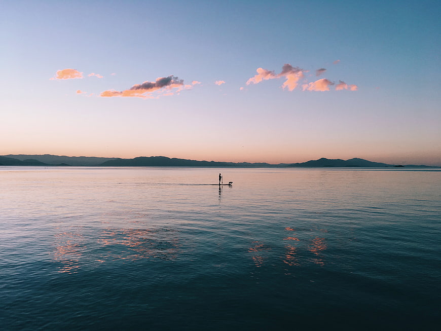 Silhouette of Stand Up Paddleboarder on Calm Ocean at Sunset