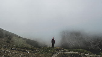 Lone Hiker Standing on Misty Mountain Ridge