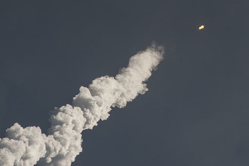 Rocket Launch Trail and Flame Against Blue Sky