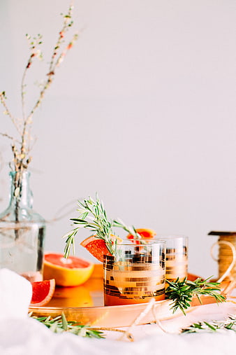 Grapefruit cocktail with rosemary garnish on gold tray