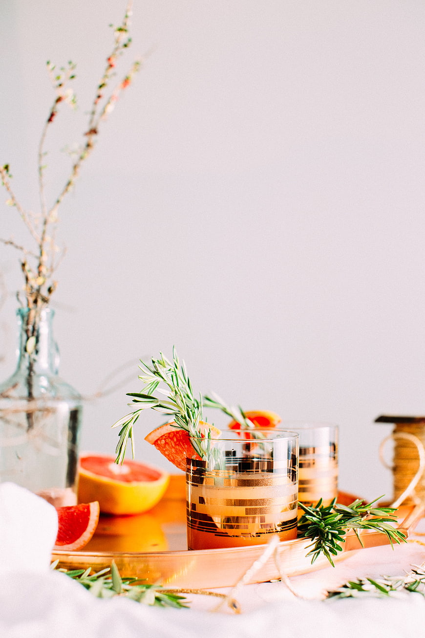 Grapefruit cocktail with rosemary garnish on gold tray