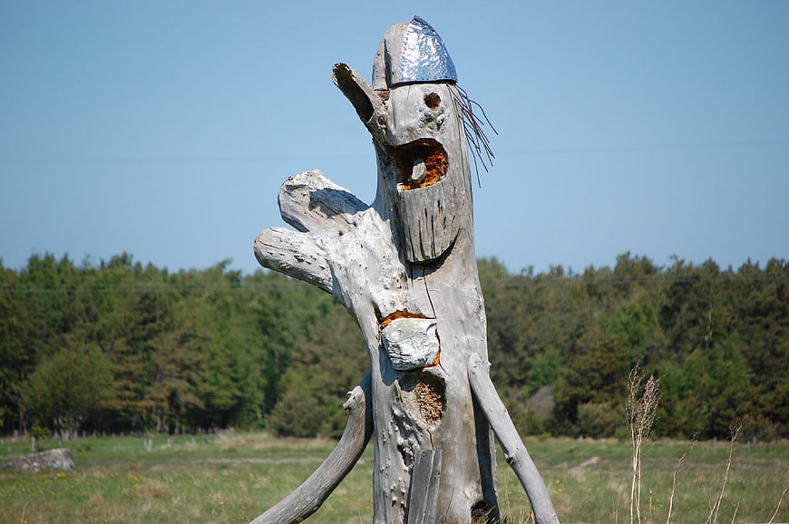 Whimsical wooden tree sculpture with silver hat in field