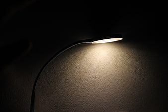 Modern LED desk lamp illuminating textured wall in dark room