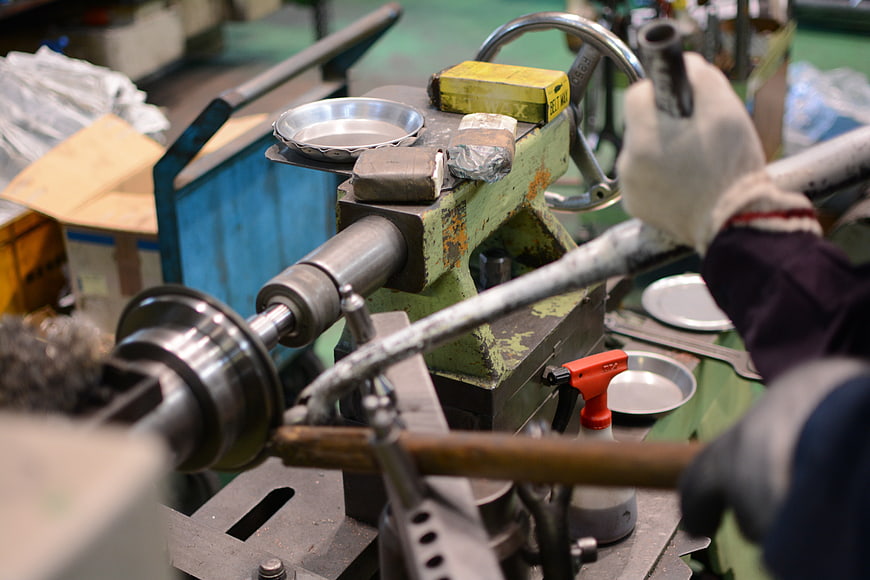 Craftsman operating metal lathe in workshop
