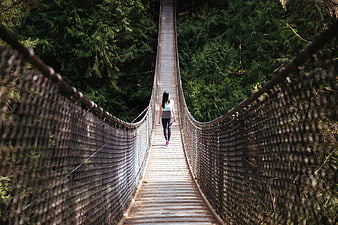 Woman Walking on Wooden Suspension Bridge in Forest