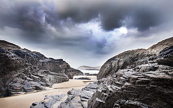 Dramatic Rocky Beach Cove Under Stormy Clouds