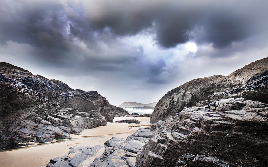 Dramatic Rocky Beach Cove Under Stormy Clouds
