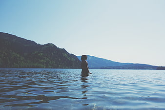 Woman Standing in Lake Water with Mountain Background