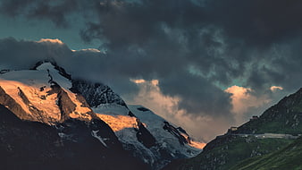 Dramatic Snow-Capped Mountain Peak at Sunset with Dark Clouds