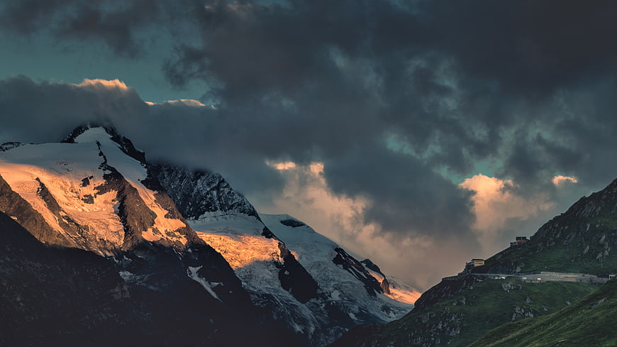 Dramatic Snow-Capped Mountain Peak at Sunset with Dark Clouds