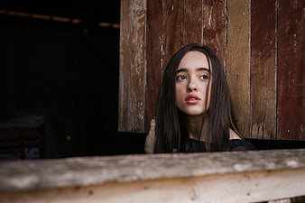 Pensive Young Woman Leaning Against Rustic Wooden Wall