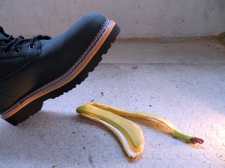 Black boot about to step on banana peel on concrete floor