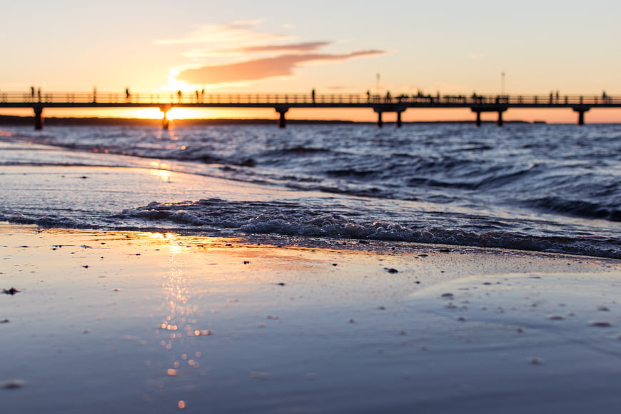 Low Angle Beach Sunset with Silhouetted Pier and Ocean Waves