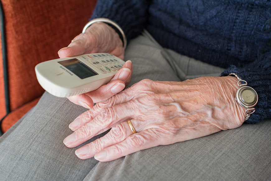 Close-up of elderly woman's hands holding a white cordless phone