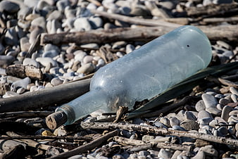 Old glass bottle with cork on pebble beach