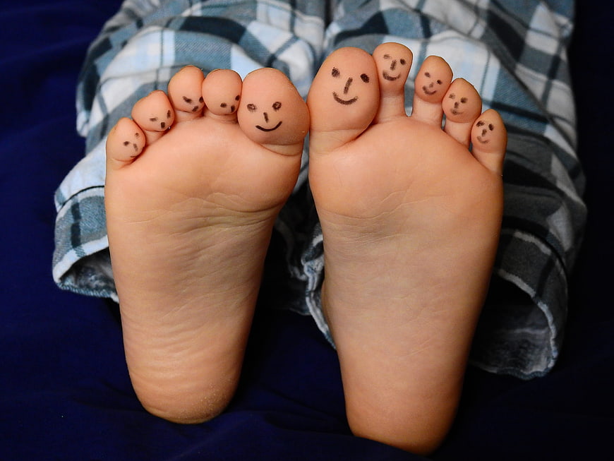 Cute baby feet with smiley faces drawn on toes