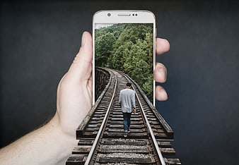 Conceptual image of man walking on train tracks emerging from smartphone screen