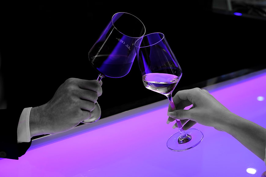 Man and Woman Toasting with Wine Glasses on Purple Bar