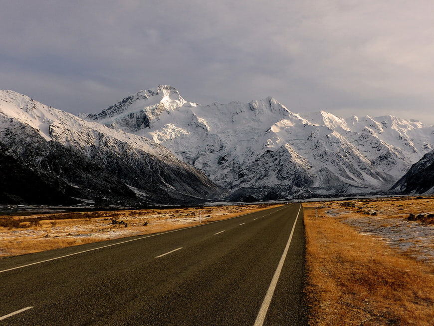 Snowy mountain highway landscape with golden grass