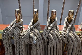 Coiled ropes on brass cleats of a sailing ship