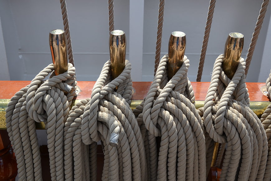 Coiled ropes on brass cleats of a sailing ship