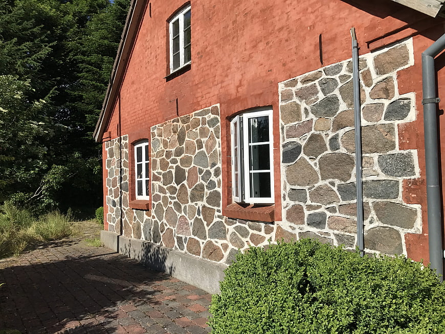 Red brick house facade with stone boulder foundation and white windows