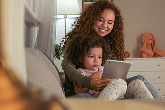 Mother and daughter using tablet together on couch