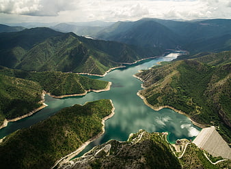 Aerial view of winding reservoir in green mountains