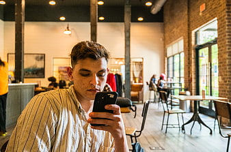Young man texting on smartphone in modern cafe