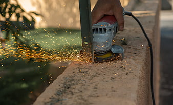 Close-up of hand using angle grinder cutting metal with sparks