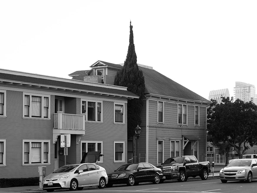 Black and white street scene with parked cars and houses