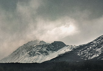 Dramatic Snow-Capped Mountain Peaks Under Cloudy Sky