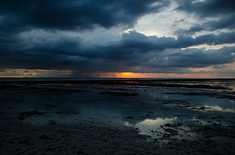 Dramatic Stormy Sunset Over Wet Beach with Cloud Reflections
