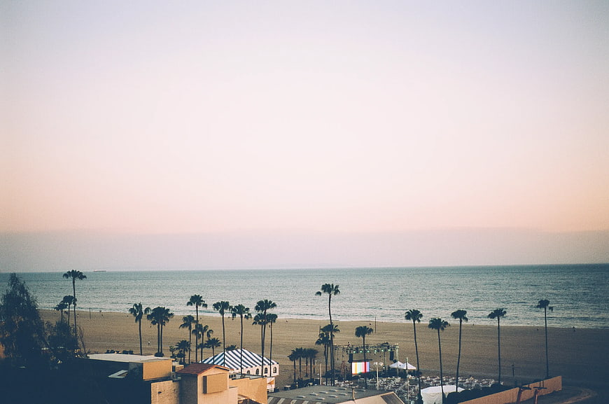 Coastal Beach View with Palm Trees and Event Stage at Sunset