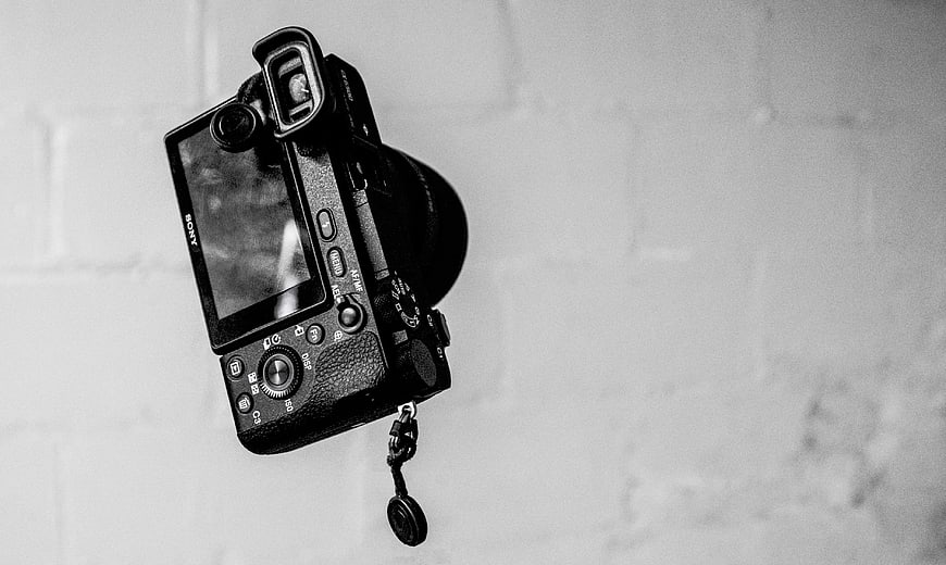 Black and white Sony camera on white brick wall