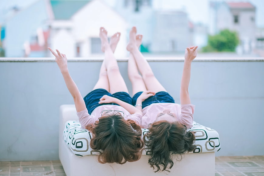 Two women relaxing on a rooftop terrace with peace signs