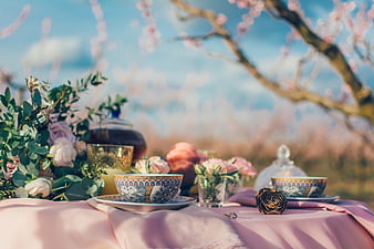 Elegant Outdoor Tea Setting With Floral Arrangement And Blossoming Tree