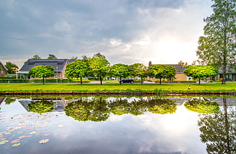 Serene suburban canal with house and tree reflections