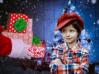 Boy in red cap looking at Christmas gifts and Santa hand
