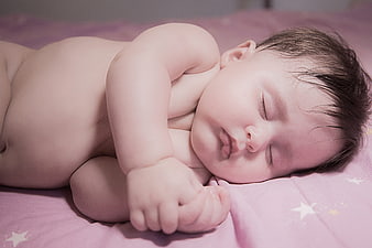 Sleeping newborn baby lying on pink star-patterned bedding