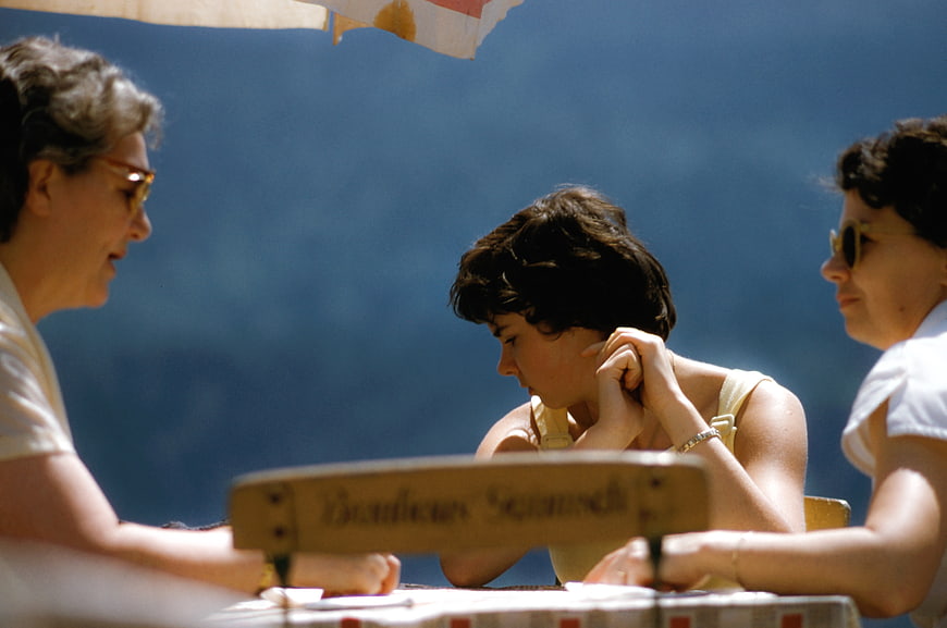 Three women sitting at a table outdoors in vintage style